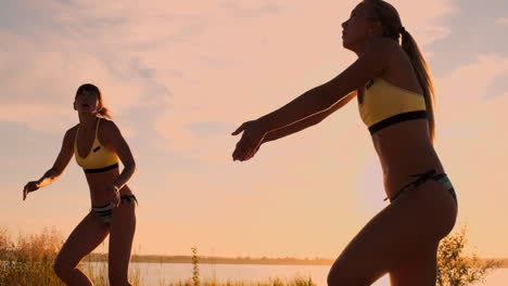 Athletic-girl-playing-beach-volleyball-jumps-in-the-air-and-strikes-the-ball-over-the-net-on-a-beautiful-summer-evening.-Caucasian-woman-score-a-point.